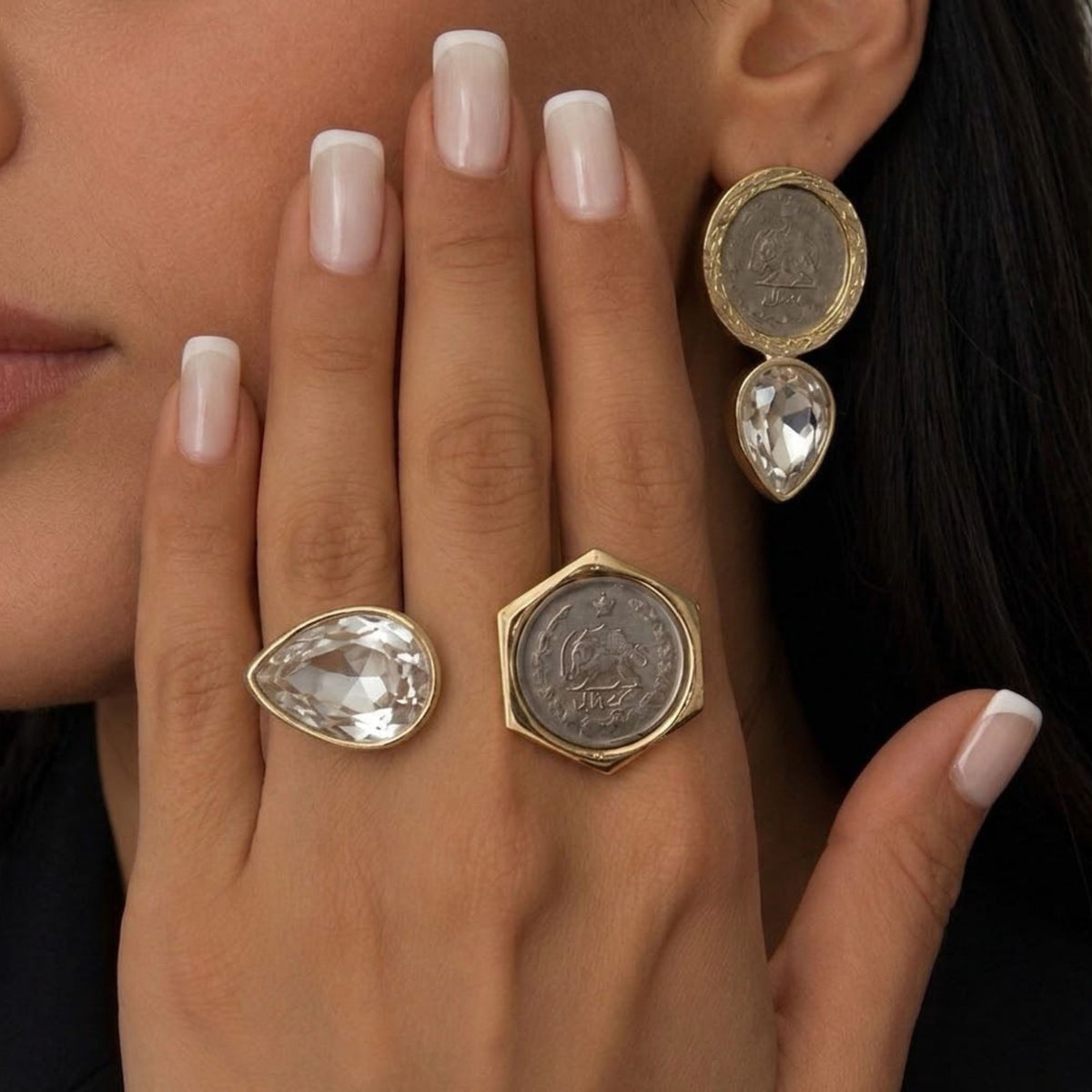 Model wearing matching vintage coin clear crystal earrings and matching adjustable fashion rings with a gold-tone finish.