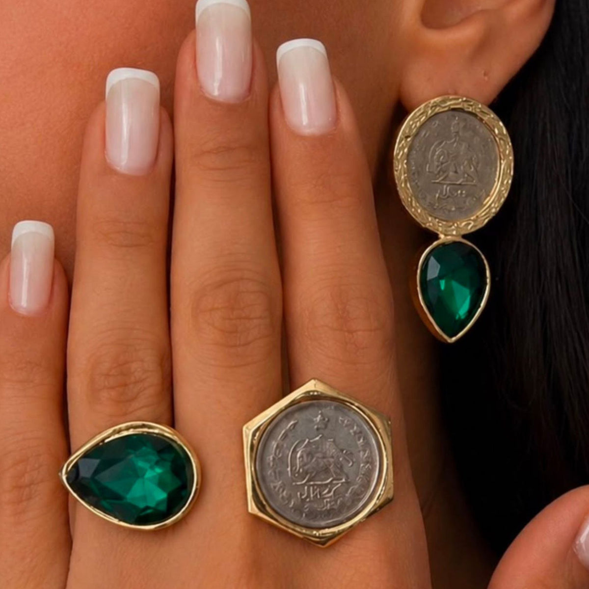 Model wearing matching vintage coin green emerald crystal earrings and matching adjustable fashion rings with a gold-tone finish.