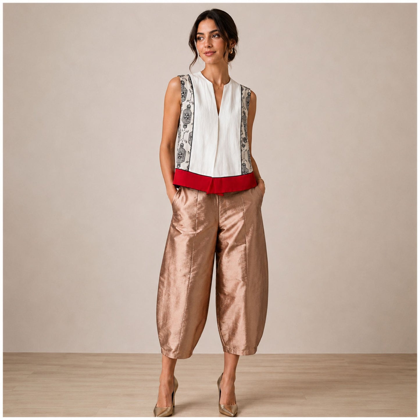 Model wearing high-waisted rose gold satin-finish taffeta cropped barrel-leg pants styled with a patterned sleeveless vest in a luxury boutique