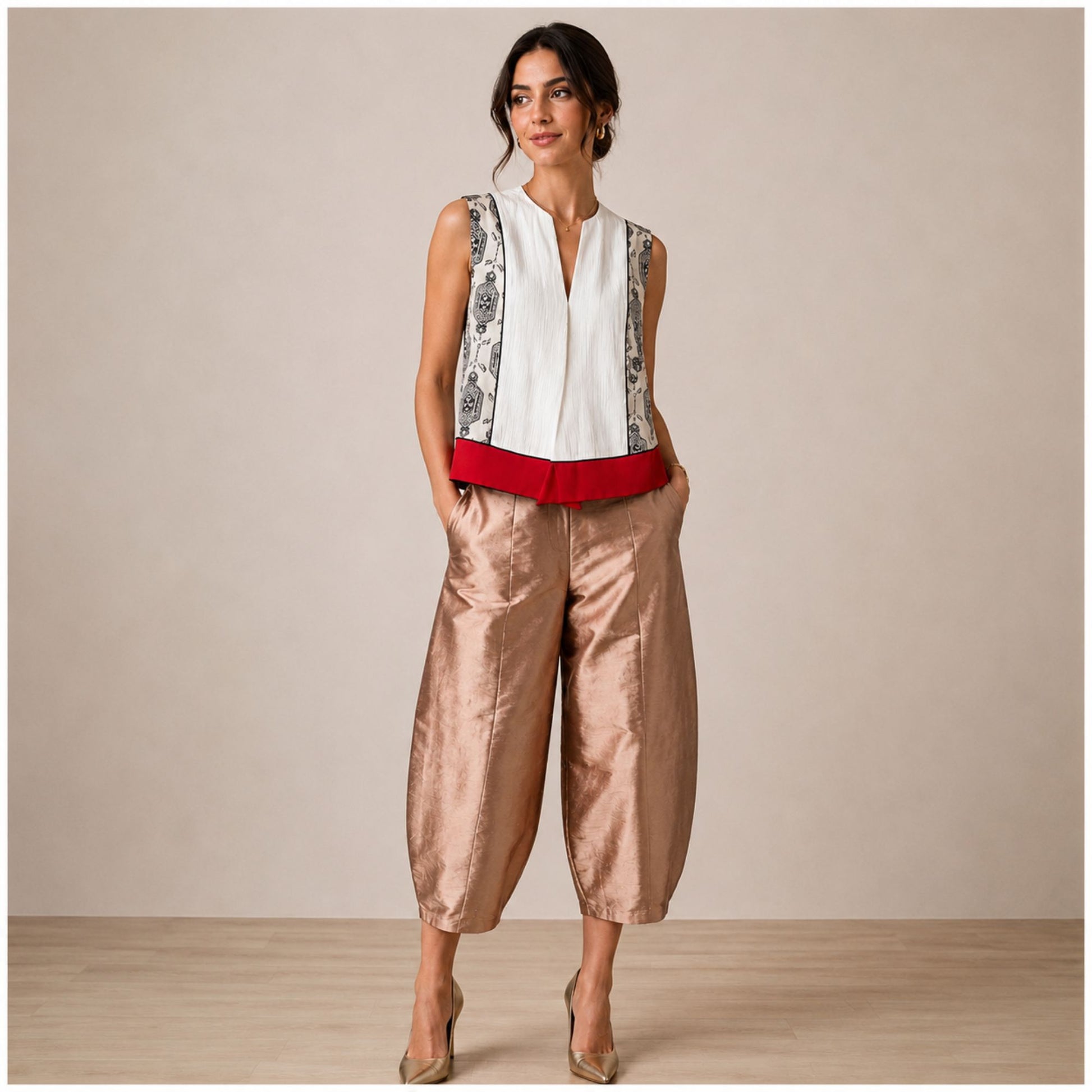 Model wearing high-waisted rose gold satin-finish taffeta cropped barrel-leg pants styled with a patterned sleeveless vest in a luxury boutique