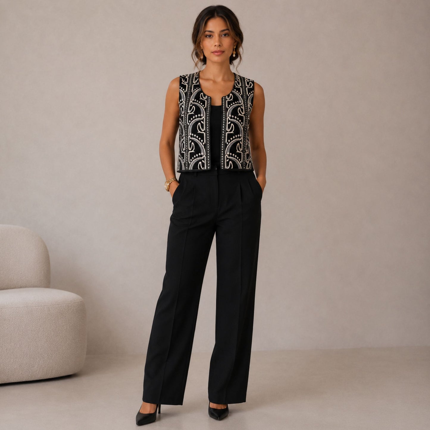 Full-length view of a model wearing a black embroidered layering vest paired with tailored black pants.