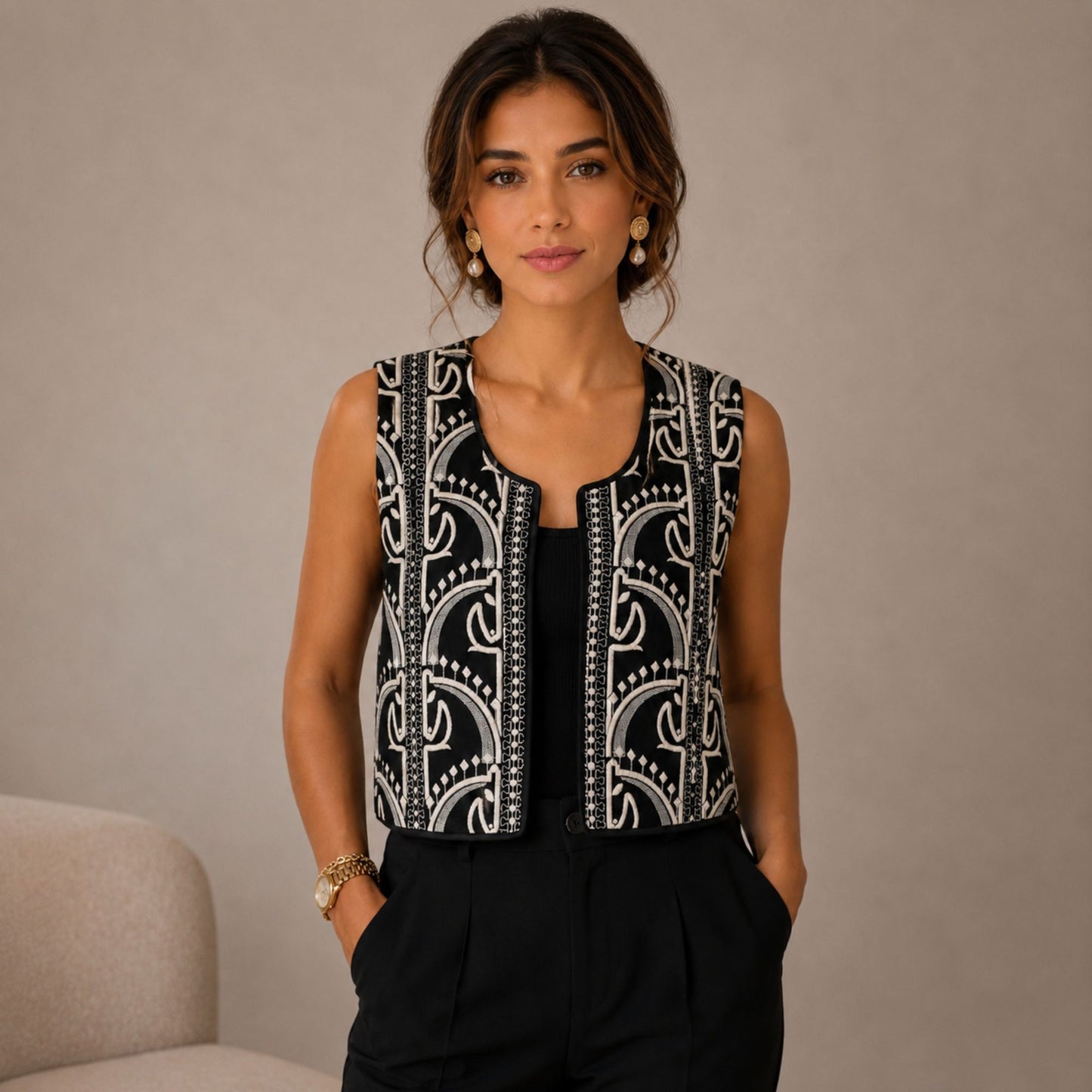 Woman wearing a black and ivory embroidered statement vest styled with black trousers in an elegant boutique fashion look