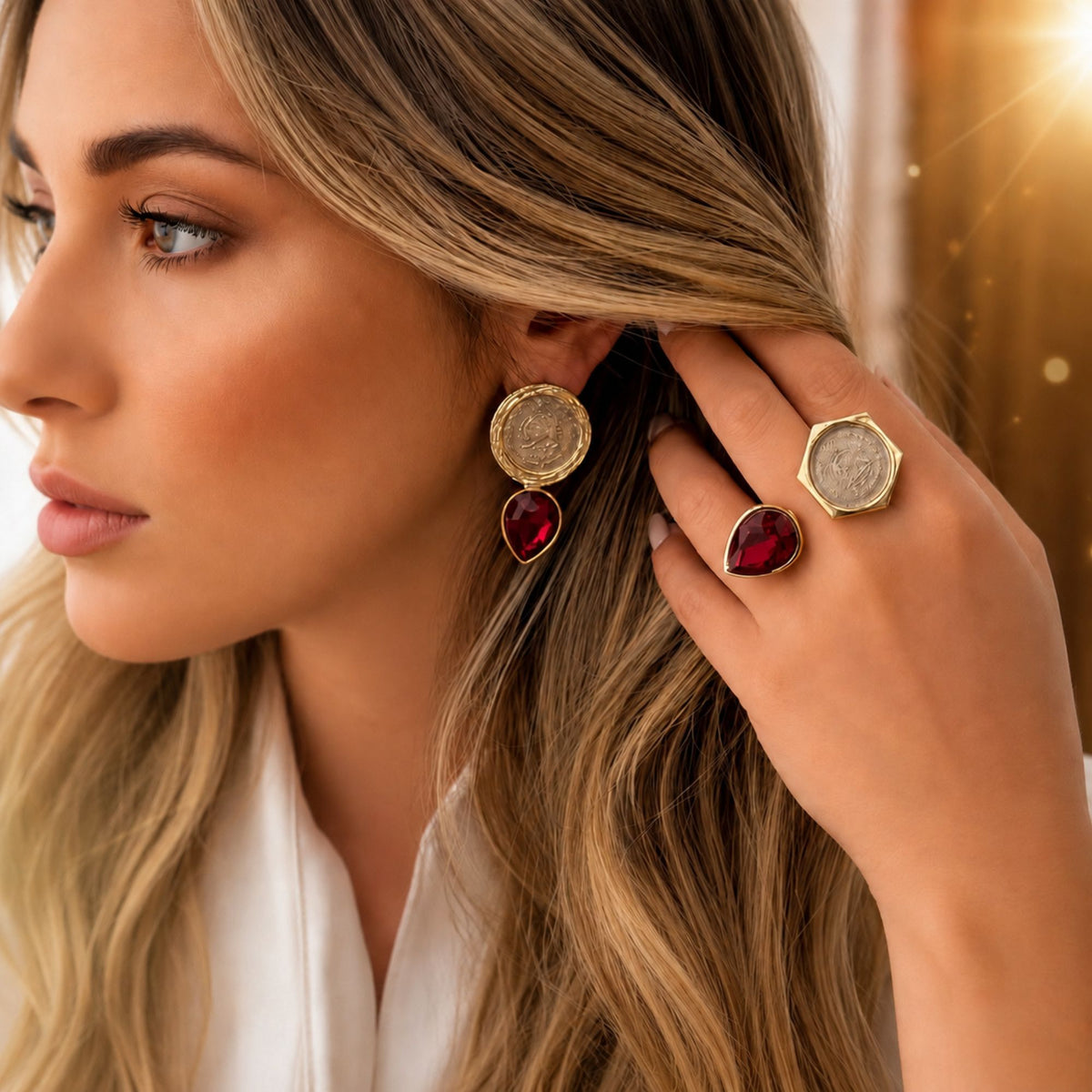 Model wearing matching coin ruby red crystal earrings and matching adjustable fashion ring with a gold-tone finish.