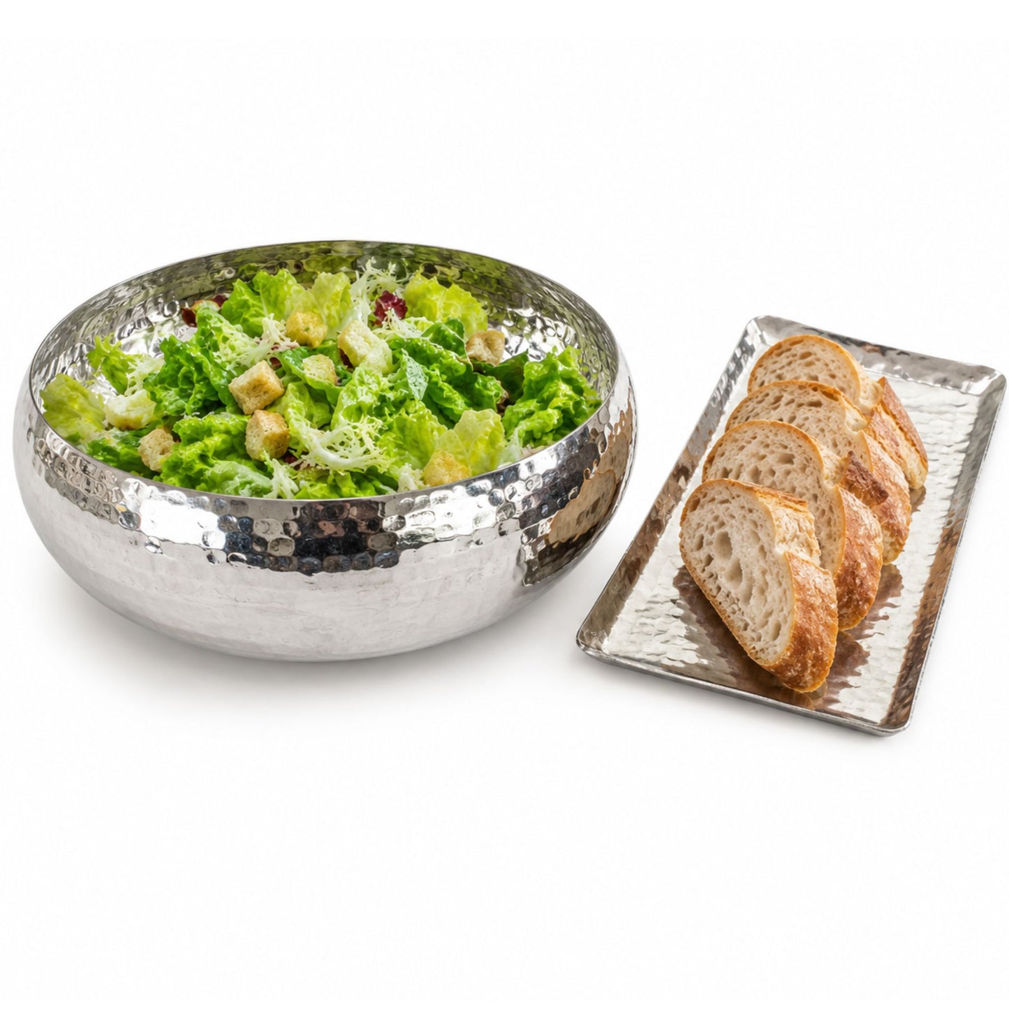 Large hammered white copper serving bowl with fresh salad beside artisan bread tray.