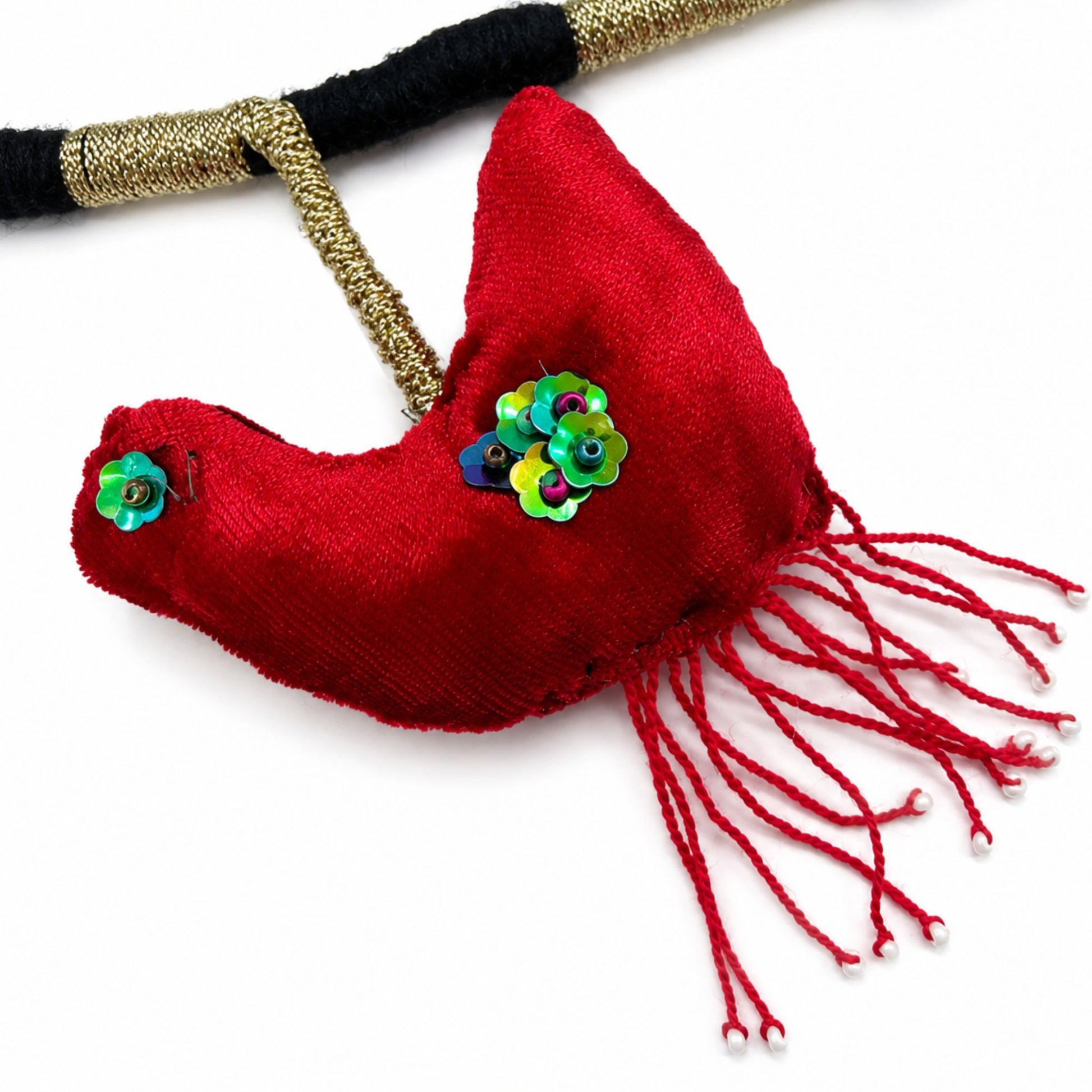Detailed view of a handcrafted red textile bird charm with tassel accents on a wearable phone strap necklace