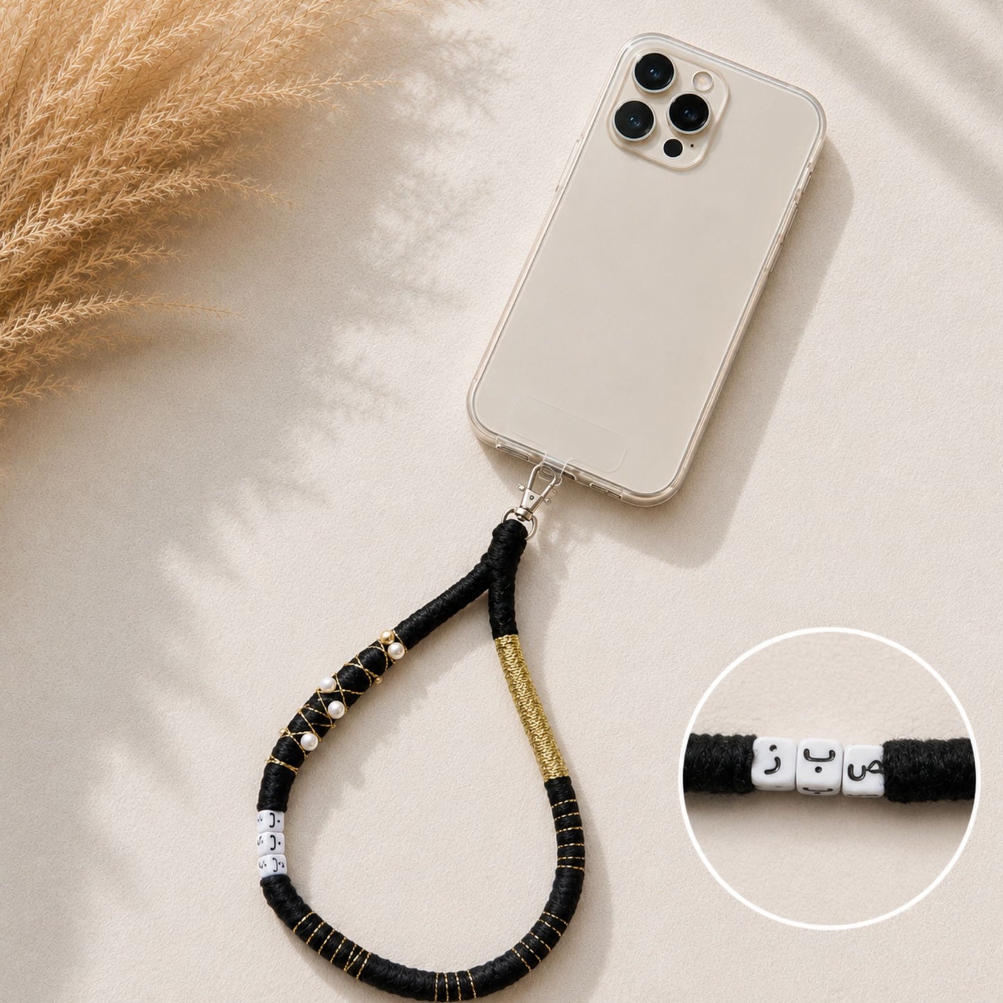 Black handmade fabric wrapped phone strap with pearl bead accents and gold thread detailing.