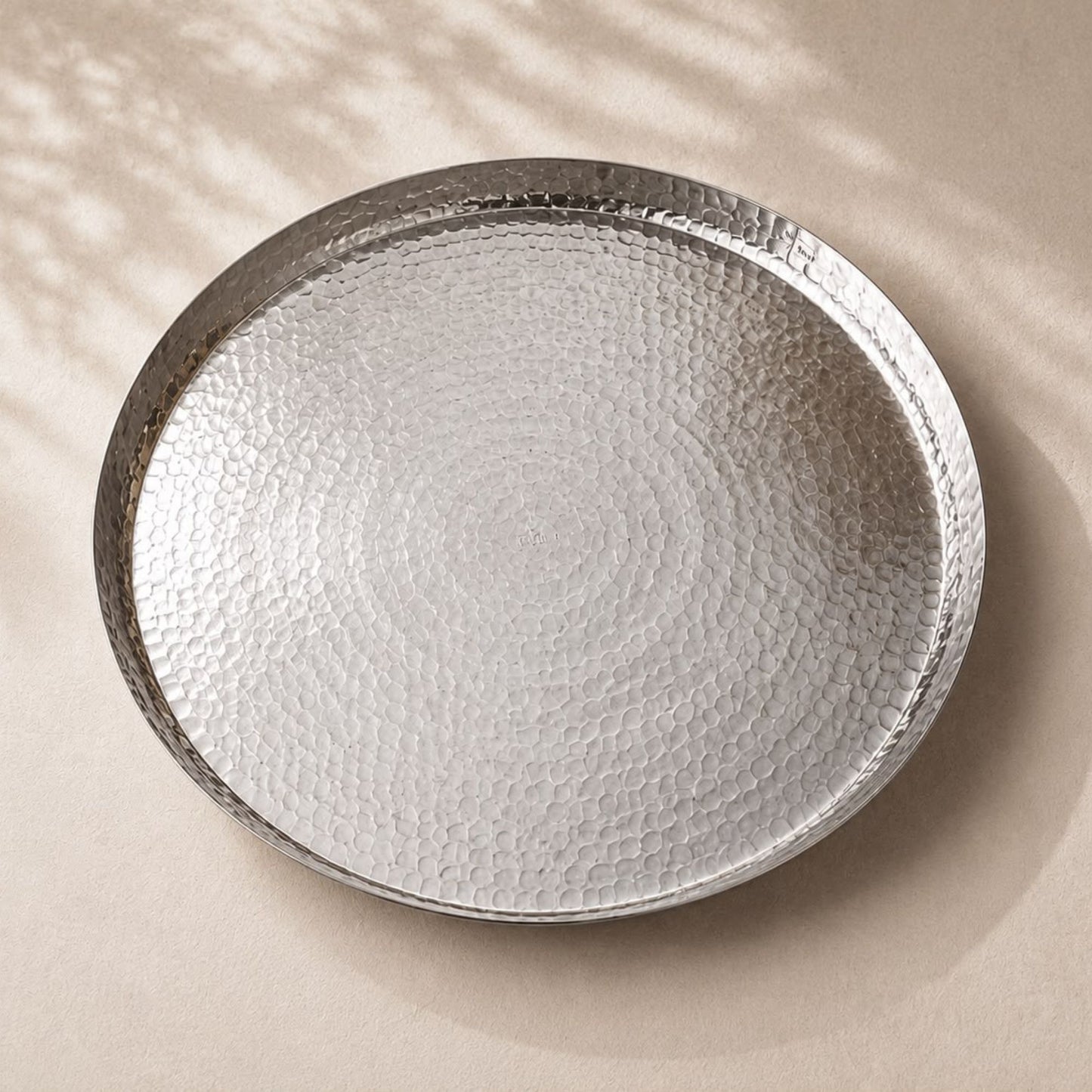 Handmade hand-hammered large white copper serving tray measuring 17.5 inches in diameter with raised rim.