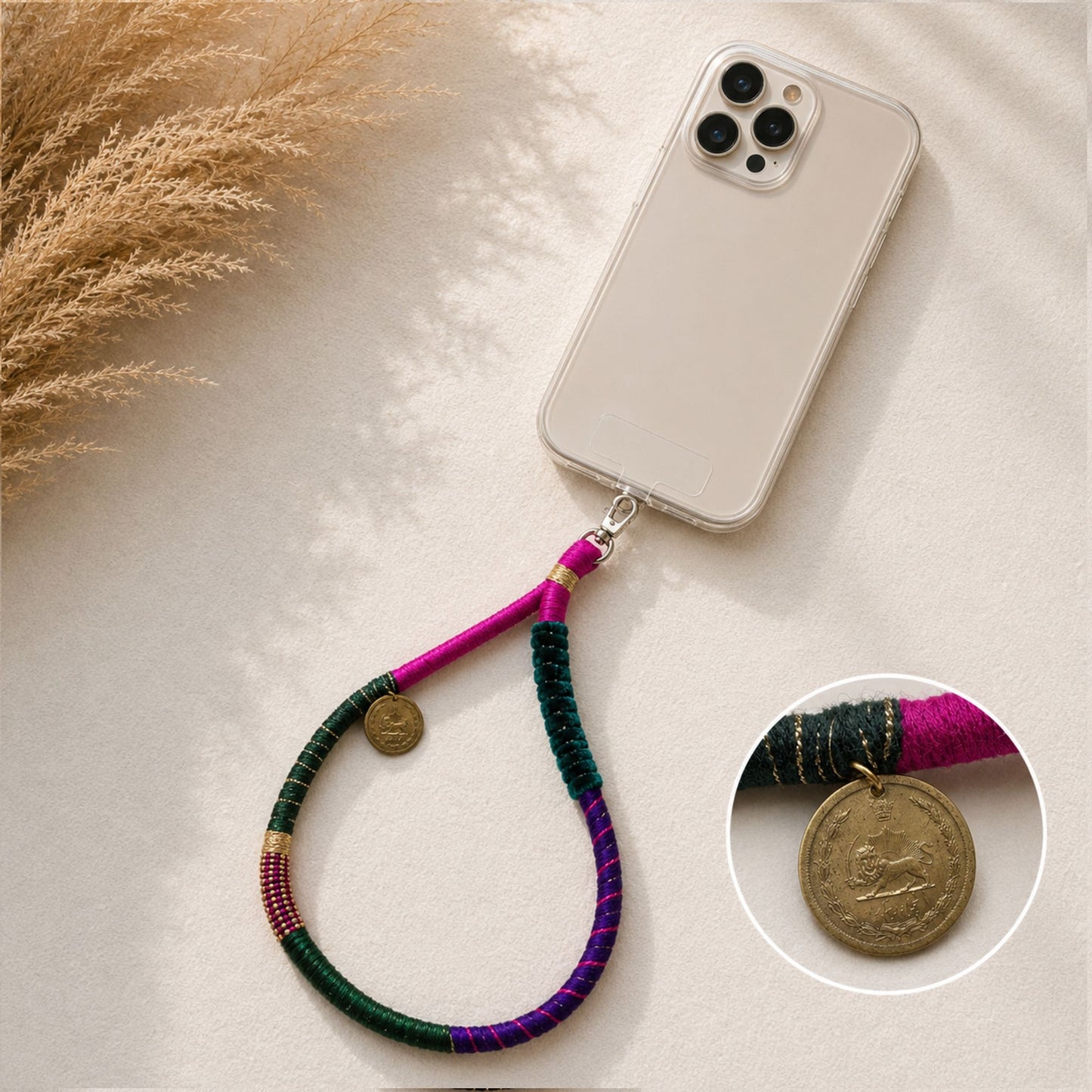 Colorful handmade boho phone wrist strap with lion coin charm and jewel-tone fabric wrapping.