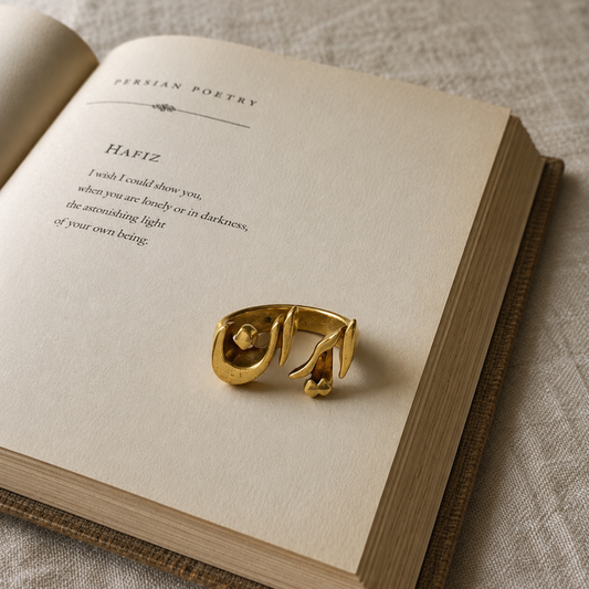 Gold-tone Iran Persian calligraphy fashion ring displayed on an open Hafiz poetry book, showcasing elegant Persian-inspired design and cultural artistry