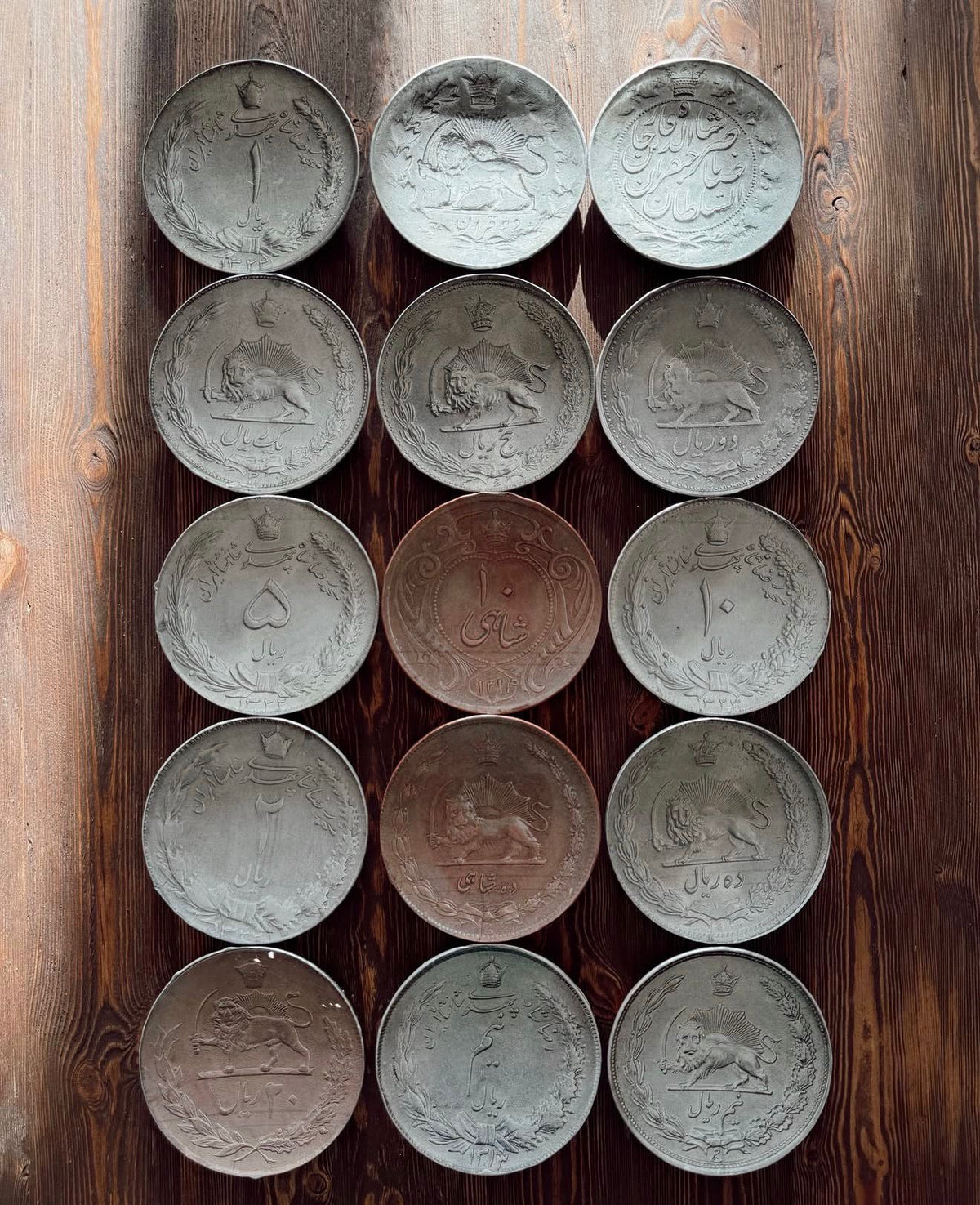Collection of vintage coin plates arranged in a grid on a wooden surface