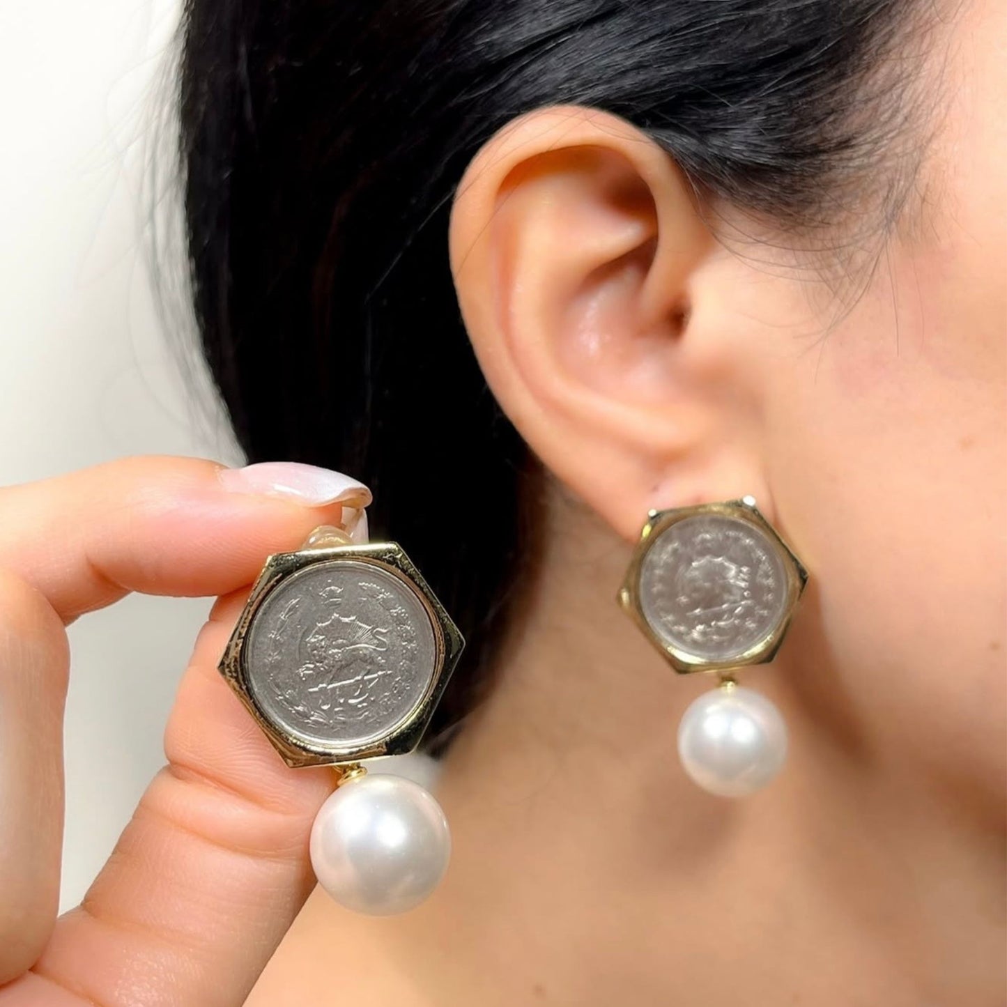 Elegant handmade style gold and pearl drop earrings on neutral background