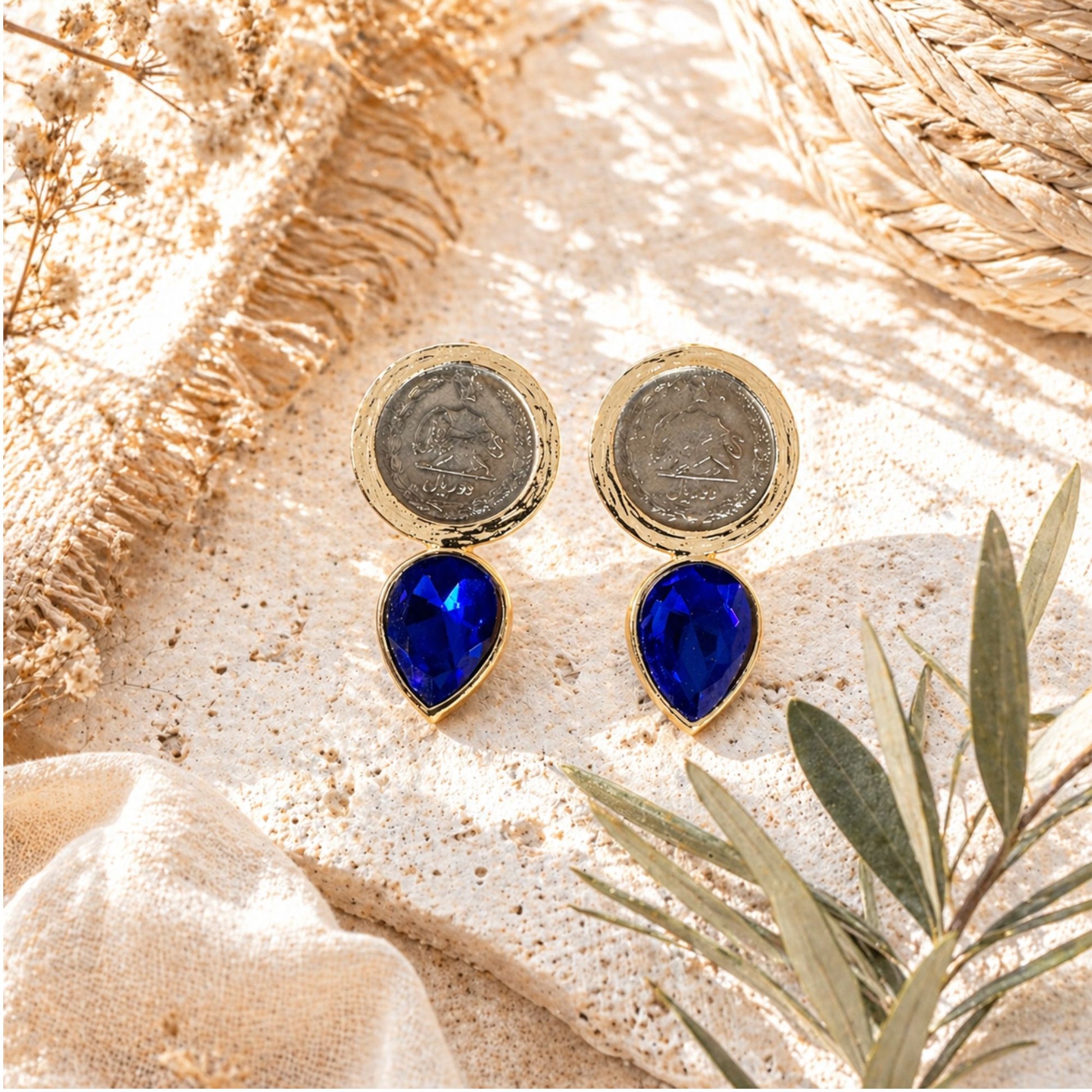 blue teardrop stones and gold accents on a textured surface with pahlavi era coins shiro khorshid