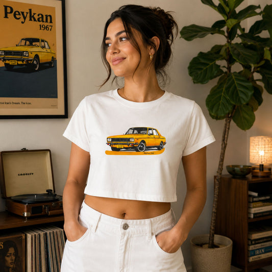 Woman wearing a white Peykan 1967 vintage car graphic crop top featuring a classic yellow Peykan automobile illustration.
