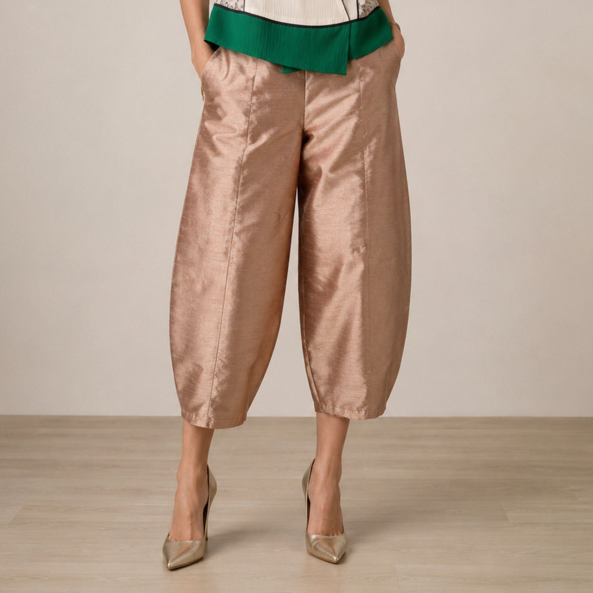High-waisted rose gold satin-finish taffeta cropped barrel-leg pants shown from the waist down, highlighting the modern silhouette and luxurious sheen