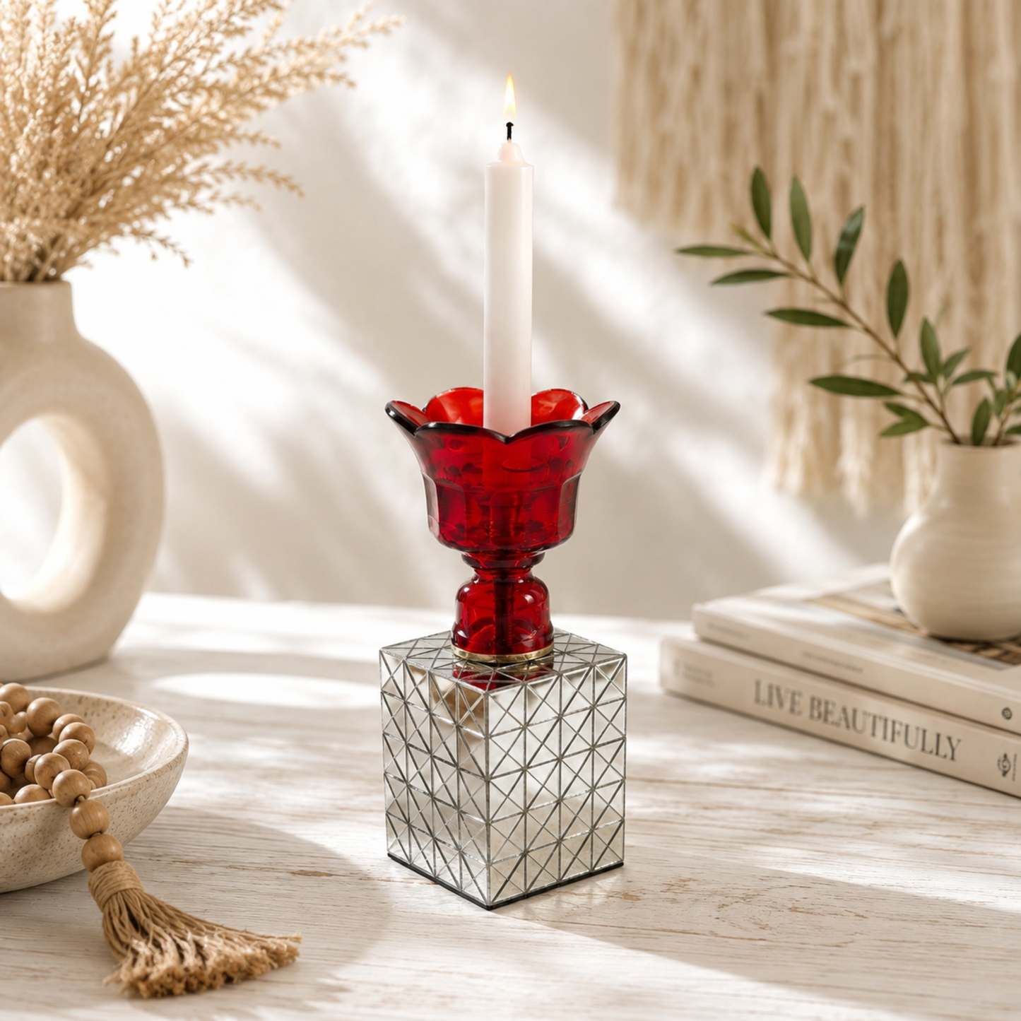 Handcrafted Ruby Red glass candle holder with a mirrored mosaic cube base styled on a bright boho coffee table.