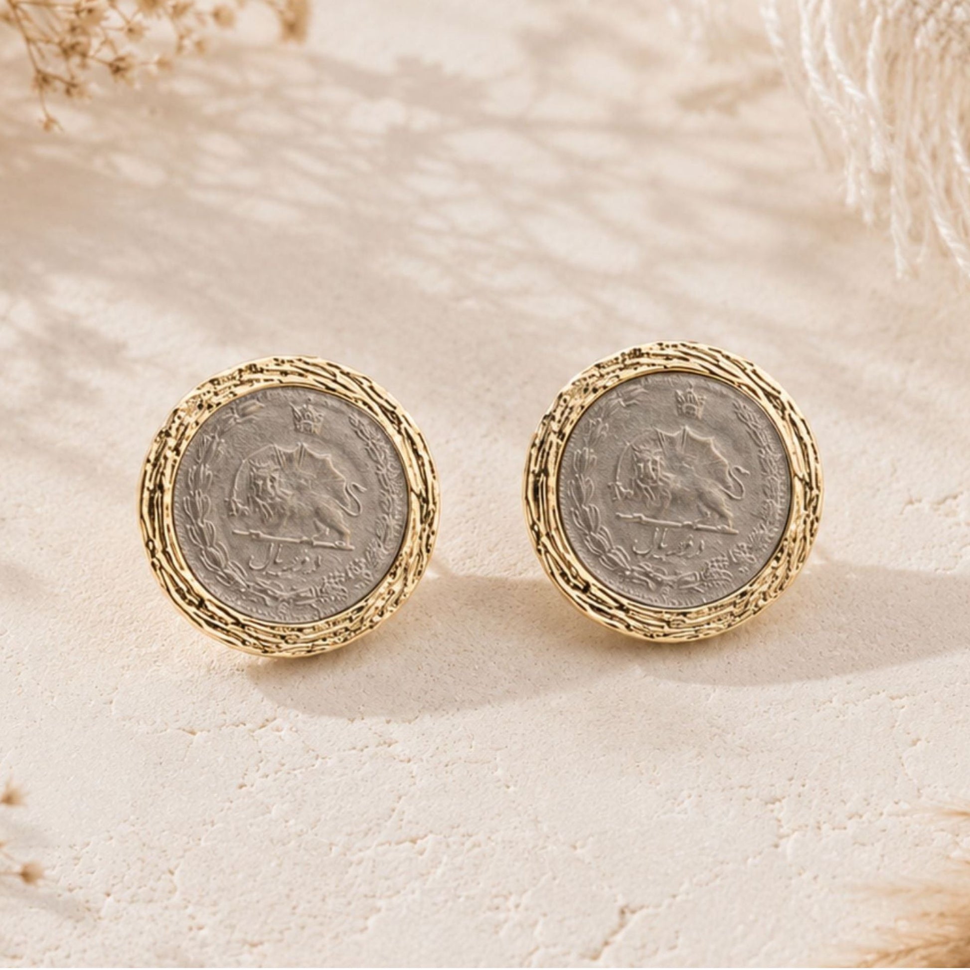 Close-up of vintage Pahlavi coin earrings with silver center and textured gold-tone border