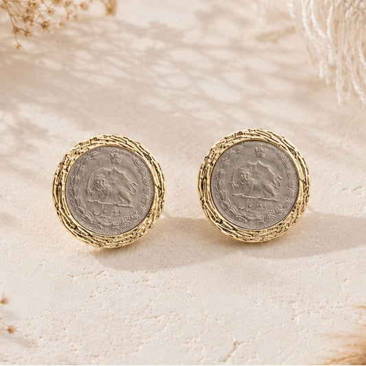 Close-up of vintage Pahlavi coin earrings with silver center and textured gold-tone border