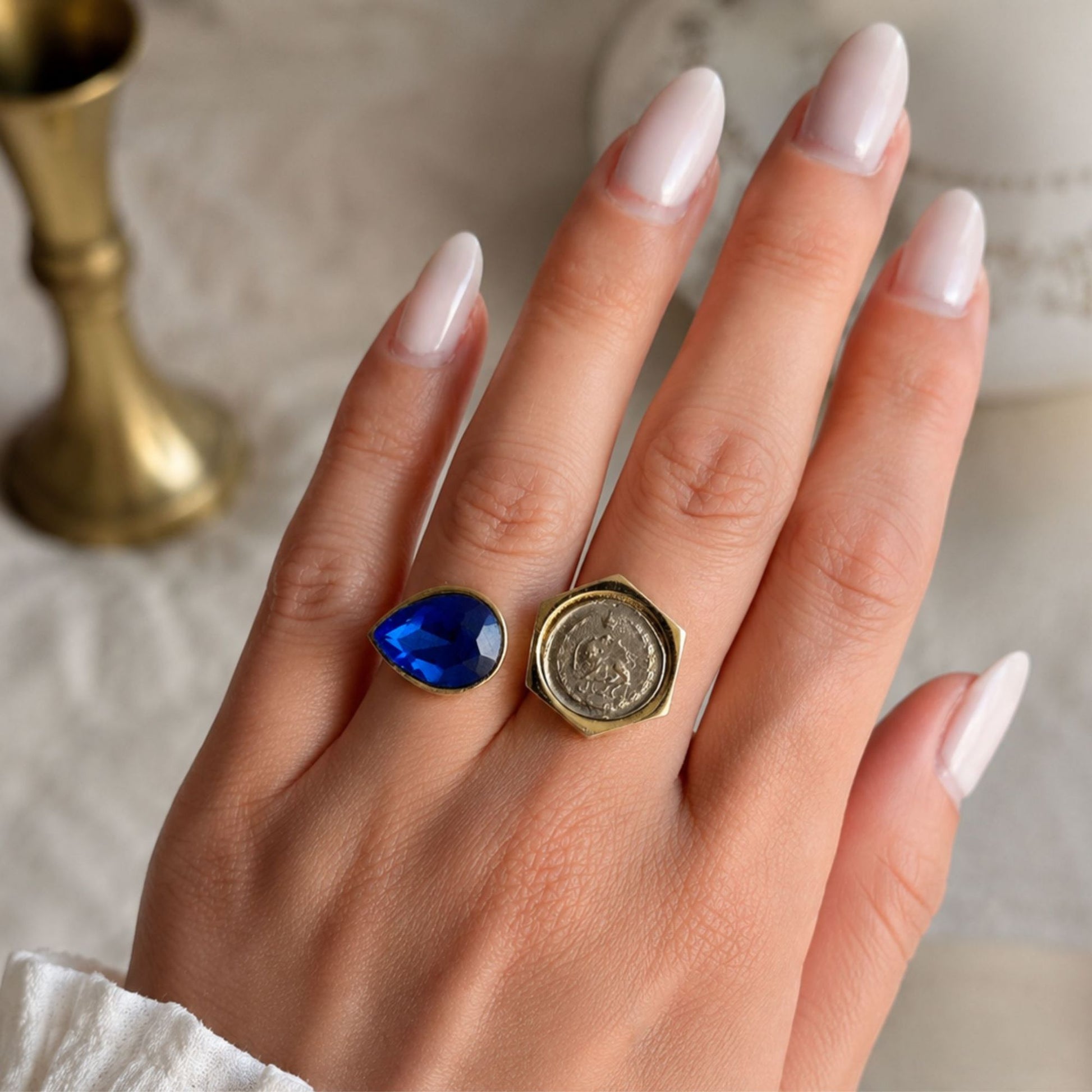 Adjustable fashion ring featuring a vintage-inspired coin and sapphire blue teardrop crystal worn on a model's hand.