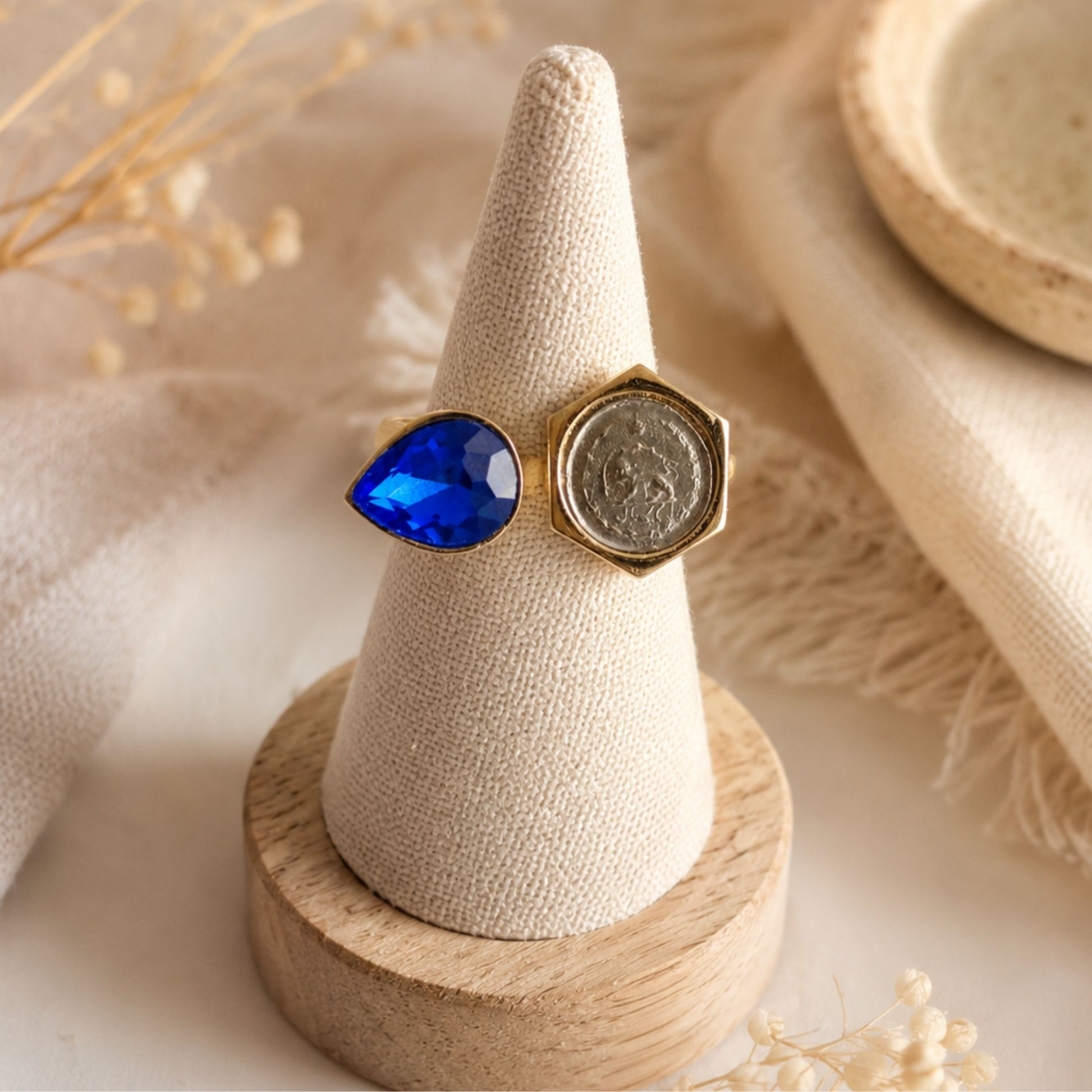 Vintage coin and sapphire blue teardrop crystal adjustable fashion ring displayed on a linen ring holder with a neutral boho background
