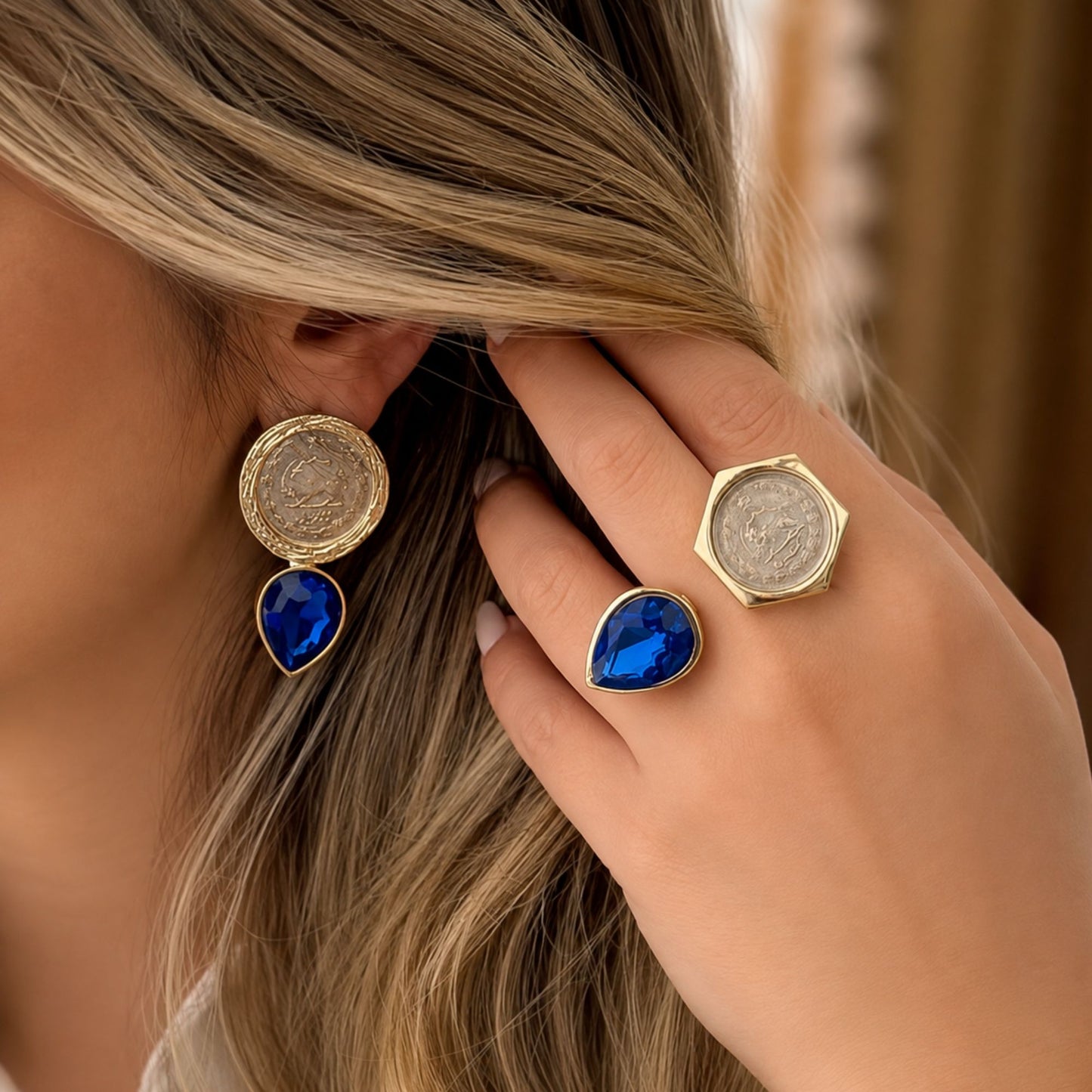 Model wearing matching vintage coin sapphire blue crystal earrings and adjustable fashion rings with a gold-tone finish.