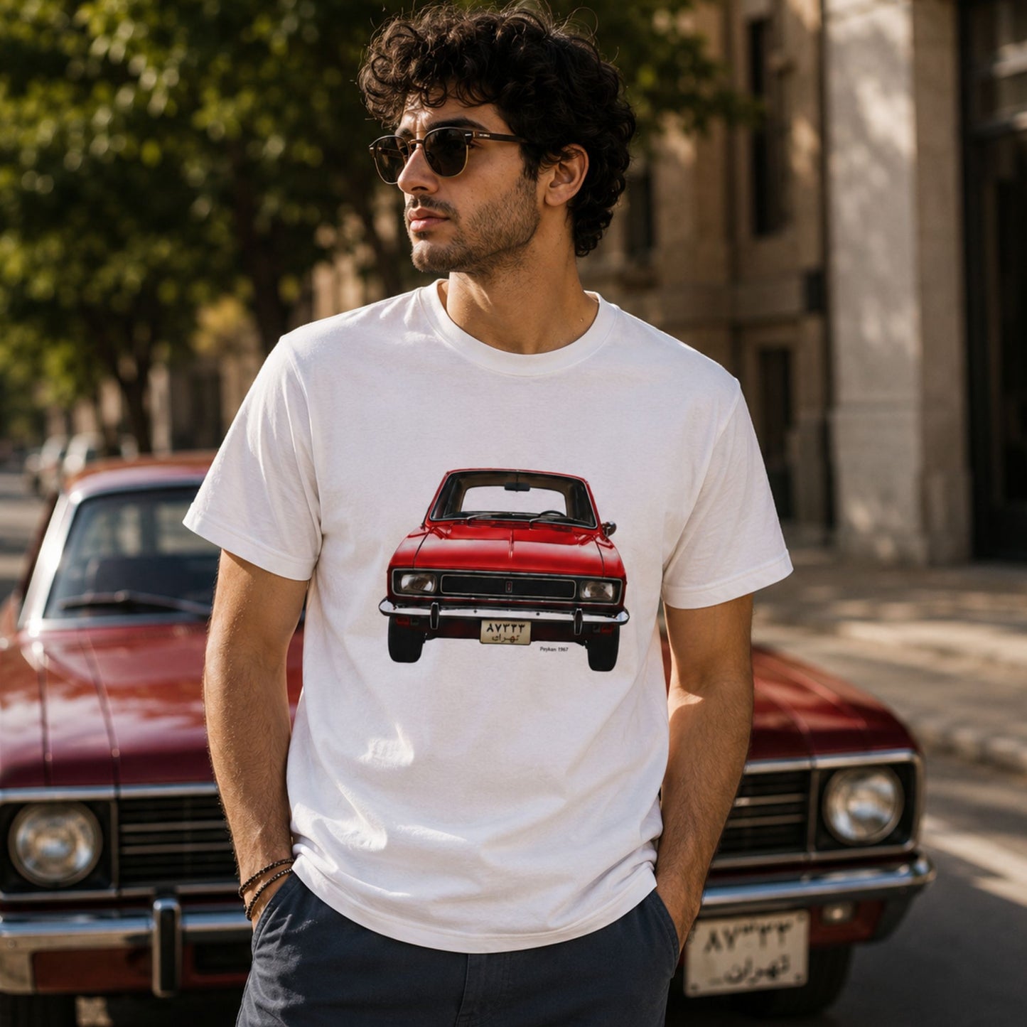 Vintage Peykan 1967 graphic t-shirt worn by a male model, featuring a red classic Persian automobile design on a white unisex tee